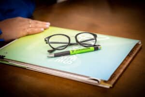 A pair of black eye glasses sitting on top of a James Moore branded folder.
