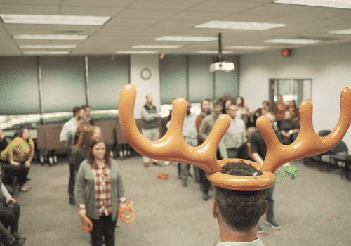 Ken wearing inflatable antlers while Katie prepares to toss rings at him