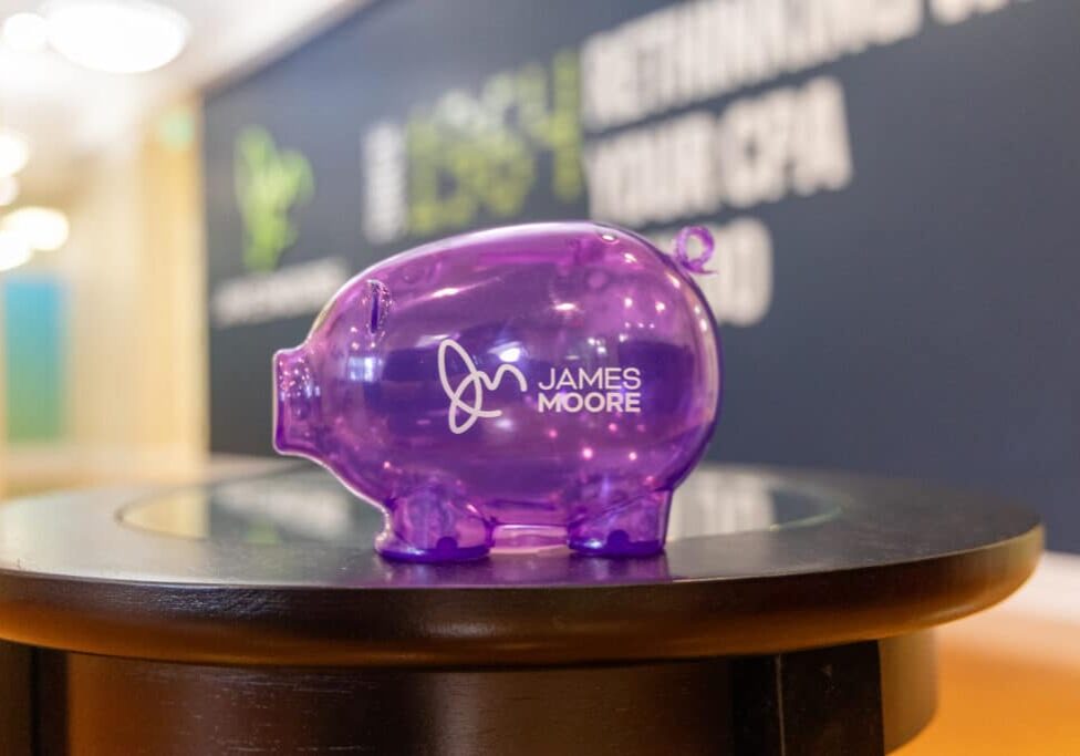 A purple piggy bank with James Moore branding.